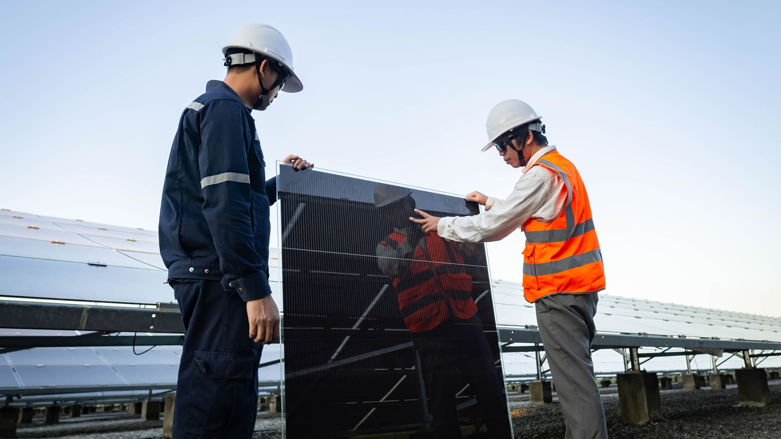 Two solar engineers holding black solar panel