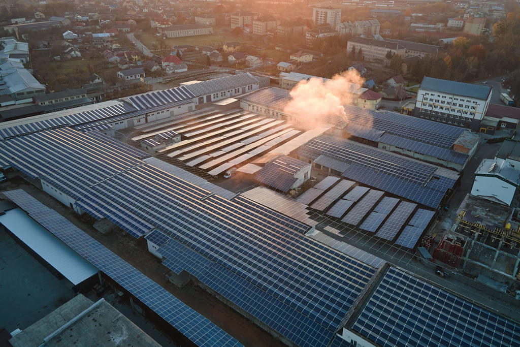 Aerial view of photovoltaic solar panels mounted on industrial building roof for producing green ecological electricity.